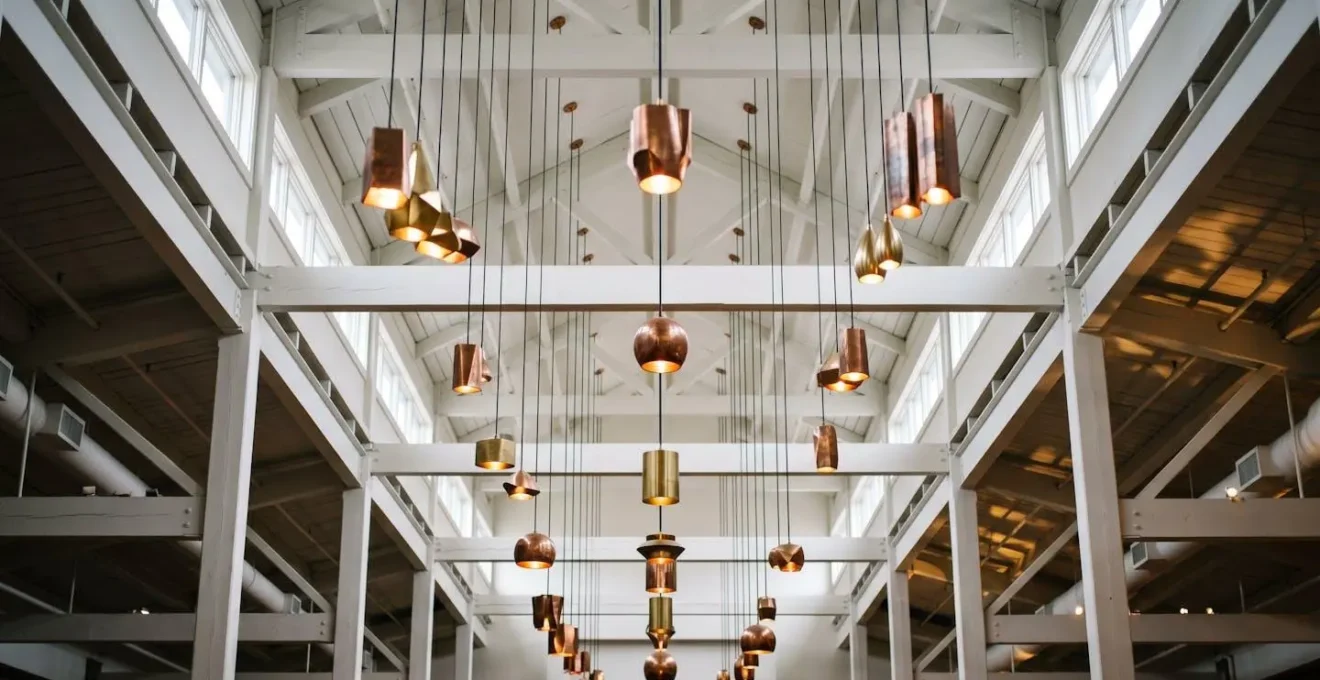 Vue en contre-plongée de luminaires sculpturaux suspendus à différentes hauteurs dans un salon à plafond cathédrale